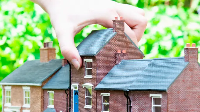 Person selecting model house --- Image by © Simon Potter/cultura/Corbis