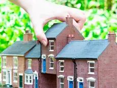 Person selecting model house --- Image by © Simon Potter/cultura/Corbis