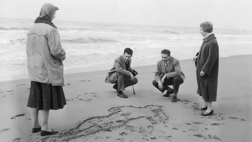 03 Apr 1957, Italy --- Unidentified spectators examine the design traced in the sand showing the spot where the body of Wilma Montesi was found almost four years ago, in Torvajanica. Members of the court investigating the case, which developed into a scandal that almost toppled the government as a result of the vice-prime minister's son, Piero Piccioni, being accused in Montesi's death, recently paid a visit to the site. Piccioni and another accused man, Ugo Montagna, were later absolved of the crime. | Location: Torvajanica, Italy. --- Image by © Bettmann/Corbis