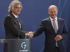 inge la mano al cancelliere tedesco Olaf Scholz