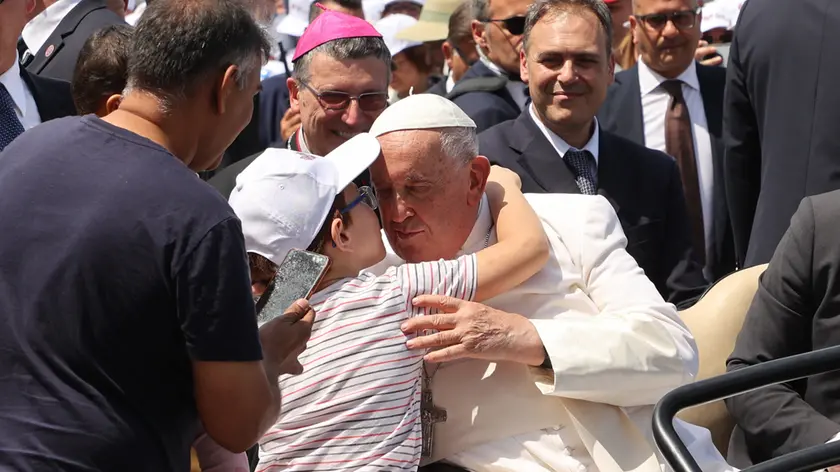 Il Papa saluta un bambino a Trieste: il vescovo Trevisi sorridente assiste alla scena