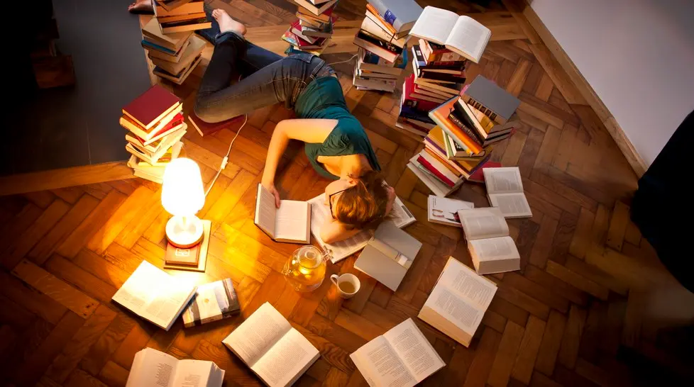 Young woman lying and sleeping on floor, surrounded by books --- Image by © Matthias Tunger/Corbis