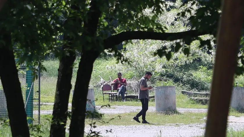 In alto alcuni migranti già ospitati a Campo Sacro, sopra il cartello della frazione e dell’ex Ostello Foto Lasorte