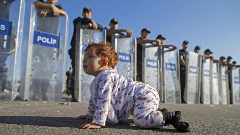 Una bimba profuga davanti alla polizia schierata