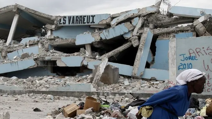 epa01995704 A woman walks by a destroyed building in Cite Soleil site in Port-au-Prince, Haiti, on 19 January 2010, after the devastating 7.0 earthquake hit the country on 12 January 2010. Offers of help continued to flow into earthquake-ravaged Haiti as the situation in capital Port-au-Prince continued to deteriorate. EPA/ORLANDO BARRIA