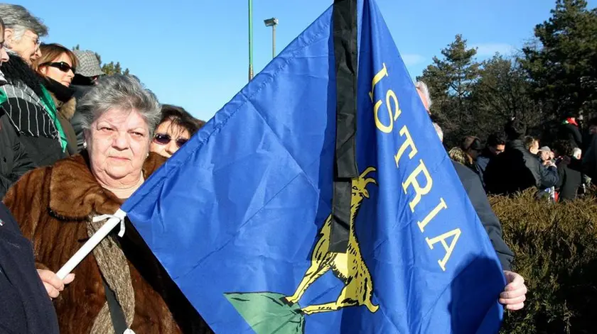 20050210 - TRIESTE - POL - FOIBE: STUDENTI LAZIO CANTANO INNO MAMELI - SONO I PRIMI IN VISITA ISTITUZIONALE A BASOVIZZA - Una donna con con la bandiera dell'Istria e un drappo nero in segno di lutto oggi alla 'Foiba Grande' di Basovizza durante la cerimonia di commemorazione delle vittime in occasione della prima giornata del ricordo. ANDREA LASORTE/ANSA/TO