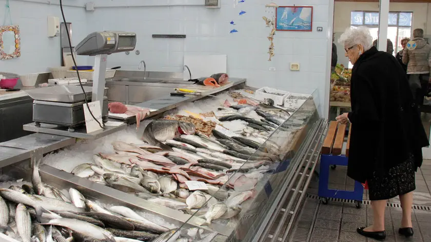 Una signora guarda il banco del pesce al mercato coperto (foto di Katia Bonaventura)