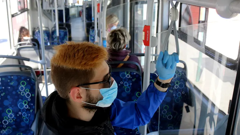 A man uses facial mask and gloves while riding on a public bus as a preventive measure against the coronavirus in Miskolc, Hungary, Thursday, April 23, 2020. As part of the protection against the coronavirus epidemic, a mandatory mask wearing was introduced on the vehicles of the Miskolc City Transportation Company. (Janos Vajda/MTI via AP)