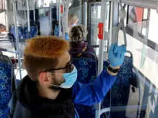 A man uses facial mask and gloves while riding on a public bus as a preventive measure against the coronavirus in Miskolc, Hungary, Thursday, April 23, 2020. As part of the protection against the coronavirus epidemic, a mandatory mask wearing was introduced on the vehicles of the Miskolc City Transportation Company. (Janos Vajda/MTI via AP)