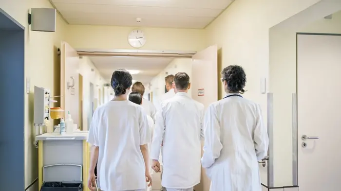 Rear view doctors and nurses walking in hospital corridor. Professional healthcare workers walking together inside the nursing home.