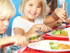 Elementary Pupils Enjoying Healthy Lunch In Cafeteria