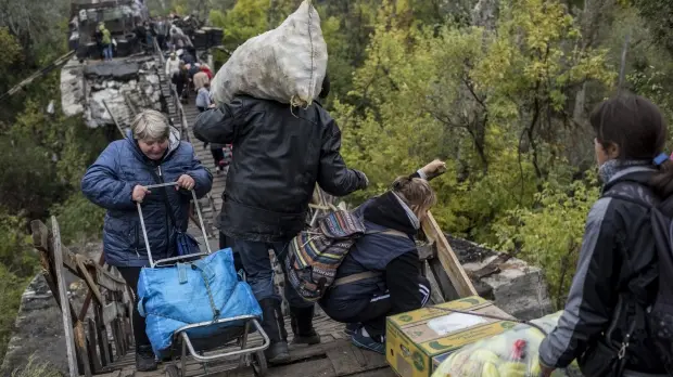 Civili mentre attraversano il ponte distrutto di Stanytsia Luhanska