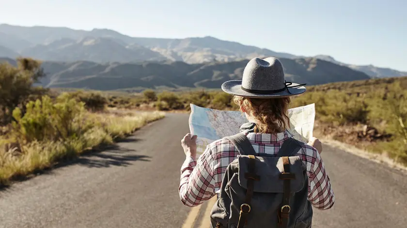 Woman standing in desert road, looking at map, Sedona, Arizona, USA