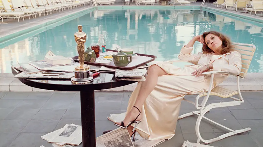 American actress Faye Dunaway takes breakfast by the pool with the day's newspapers at the Beverley Hills Hotel, 29th March 1977. She seems less than elated with her success at the previous night's Academy Awards ceremony, where she won the 1976 Oscar for Best Actress in a Leading Role for 'Network'.