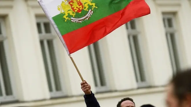 epa03591695 A man waves a national flag during a rally in support of Bulgarian Prime Minister Boyko Borisov in front of Bulgarian Parliament in Sofia, 20 February 2013. Borisov announced the resignation of his government after days of protests against its austerity policies. His center-right cabinet took office in July 2009. Several demonstrators protesting high electricity prices and low wages in Bulgaria were injured late 19 February in clashes with police. EPA/VASSIL DONEV