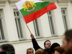 epa03591695 A man waves a national flag during a rally in support of Bulgarian Prime Minister Boyko Borisov in front of Bulgarian Parliament in Sofia, 20 February 2013. Borisov announced the resignation of his government after days of protests against its austerity policies. His center-right cabinet took office in July 2009. Several demonstrators protesting high electricity prices and low wages in Bulgaria were injured late 19 February in clashes with police. EPA/VASSIL DONEV