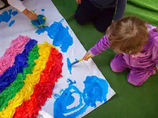 Una bambina intenta a disegnare un arcobaleno in una scuola dell’infanzia