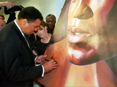 LAX99 - 19990310 - BEVERLY HILLS, CA, UNITED STATES : Muhammed Ali(L) signs a painting as its artist Caryn Fregoso(C) watches during an exhibition at the Very Special Arts Gallery West in Beverly Hills, CA 10 March 1999. Ali attended the exhibition "Strength of Greatness" at the gallery, which features works of art created by people suffering from Parkinson' Disease. The event raised money to create awareness and conduct research about the disease. EPA/ AFP PHOTO Frederick M. Brown