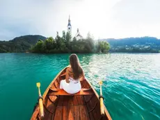 Una turista sulla caratteristica barchetta del lago di Bled ammira la chiesetta sull’isola. Bled è una delle località turistiche più gettonate