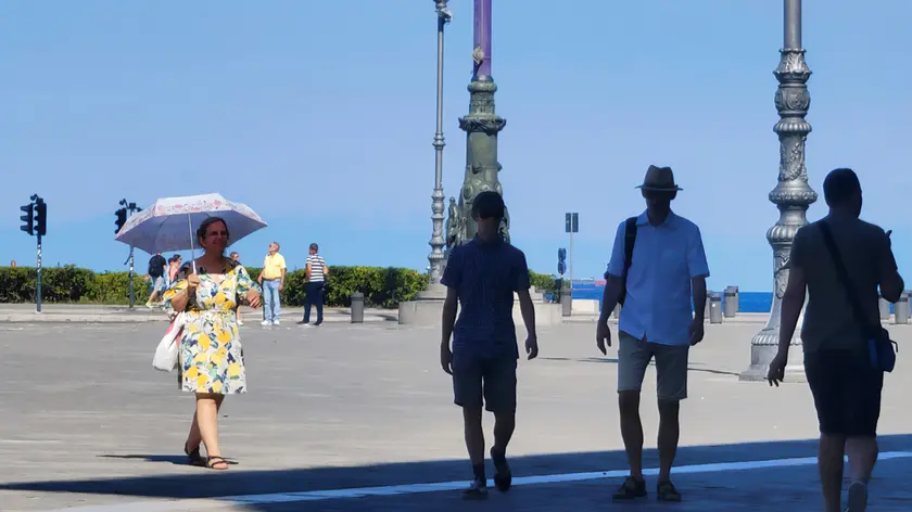 Passanti si riparano dal caldo in piazza Unità (foto di Andrea Lasorte)