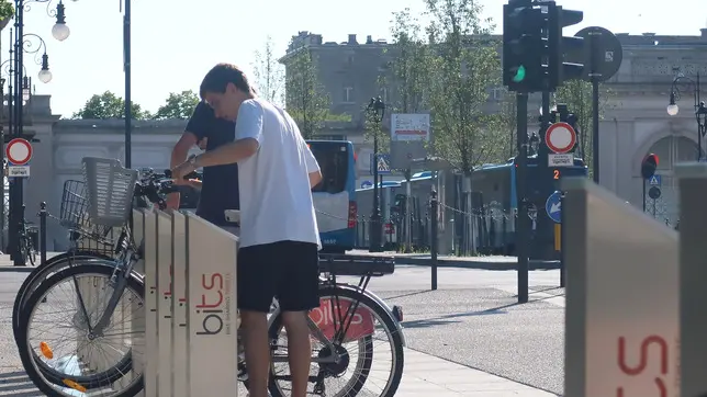 Utenti del servizio di bike sharing mentre tentano di sganciare la bici scelta dalla colonnina