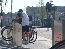 Utenti del servizio di bike sharing mentre tentano di sganciare la bici scelta dalla colonnina