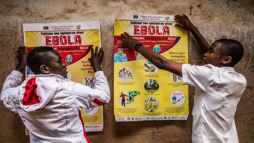 Students put a poster detailing Ebola sensitization on the walls at La Vérité school in Butembo, North Kivu, Democratic Republic of Congo on 23 March 2019. The Ministry of Health (MoH), World Health Organisation and partners remain committed to strengthening community engagement efforts to urge individuals suspected to have contracted Ebola to seek care early and improve their chances of survival, as well as to reduce the risks of transmission. However, the presence of armed groups, their activities and their increasing direct threats against Ebola response teams, including removal of leaflets and intimidation of local health workers, continue to dampen the effort in several towns of North-Kivu province.