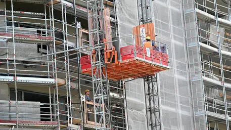 Operai edili al lavoro sulla facciata di un palazzo ricoperto da ponteggi, Milano, 14 giugno 2022. ANSA/DANIEL DAL ZENNARO
