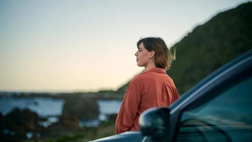 Young girl on the road trip look at beautiful landscape next to the car
