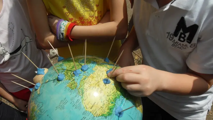 Bambini alle prese con un mappamondo: torna l'ora di geografia, ma il primo a sbagliare è il ministero...