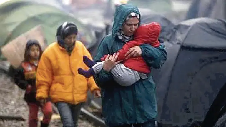 epa05202840 A refugee woman carries his baby at a refugee camp, during a rainy day, as they wait to cross the borders between Greece and Macedonia, near the village of Idomeni, northern Greece, 09 March 2016. Greece estimates that more than 25,000 migrants are presently on its territory, with more than half stuck at the makeshift camp Idomeni, on the border with Macedonia. Macedonia is on the main corridor of the Balkan route, while Bulgaria is to the east, with a far smaller numbers of transits. Countries on the Balkan route north of Greece have already been throttling down the migration flow for weeks. EPA/YANNIS KOLESIDIS