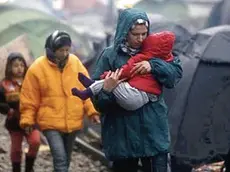 epa05202840 A refugee woman carries his baby at a refugee camp, during a rainy day, as they wait to cross the borders between Greece and Macedonia, near the village of Idomeni, northern Greece, 09 March 2016. Greece estimates that more than 25,000 migrants are presently on its territory, with more than half stuck at the makeshift camp Idomeni, on the border with Macedonia. Macedonia is on the main corridor of the Balkan route, while Bulgaria is to the east, with a far smaller numbers of transits. Countries on the Balkan route north of Greece have already been throttling down the migration flow for weeks. EPA/YANNIS KOLESIDIS