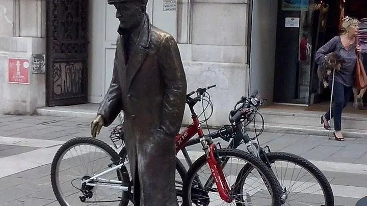 La statua di Umberto Saba con le due bici ben assicurate con tanto di lucchetto (foto della lettrice Ambra Maturani)