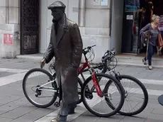 La statua di Umberto Saba con le due bici ben assicurate con tanto di lucchetto (foto della lettrice Ambra Maturani)