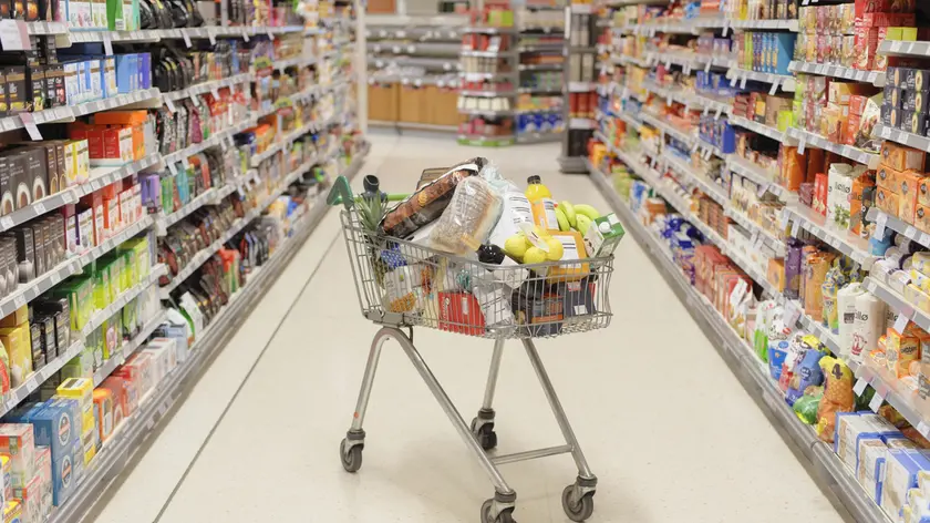 Un carrello pieno tra le corsie di un supermercato. La social card andrà spesa in generi alimentari