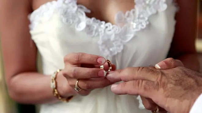 Broome, Australia --- Woman sliding wedding ring on husband's finger --- Image by © Ocean/Corbis