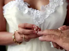 Broome, Australia --- Woman sliding wedding ring on husband's finger --- Image by © Ocean/Corbis