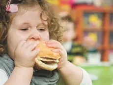 Una bimba mangia con gusto un hamburger