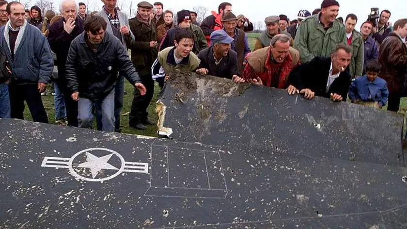 BEL06-19990328-BELGRADE, YUGOSLAVIA: : Locals from a village some 30 kilometres west of Belgrade rolling a wing of the crashed US F117 Stealth bomber Sunday 28th March 1999 during a break in the air raids. The aircraft crashed late yesterdy but it is still unclear whether it was brought down by Serb fire or a technical fault. EPA PHOTO/SRDJAN SUKI