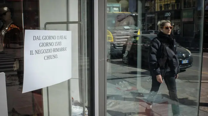 Un cartello esposto su una porta vetrata di un negozio di corso Buenos Aires informa il pubblico della momentanea chiusura dell'esercizio a causa dell'emergenza coronavirus, Milano, 11 marco 2020. In Corso Buenos Aires, un' importante strada commerciale di Milano, che si estendo su oltre 1600 metri con oltre 350 punti vendita di vari tipi di merce e una media di centomila persone ogni giorno, questa mattina metà dei negozi erano chiusi. ANSA/MATTEO CORNER
