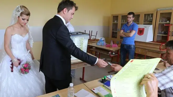 epa03756662 Newly-weds Endri Xhacka (C) and his bride Megi (L) pick their ballots at a polling station near Tirana, Albania, 23 June 2013. Albanians on 22 June vote to elect the 140 members of the Albanian Parliament. The EU will closely watch the entire elections process, they said on 17 June, stressing that 'international and European standards' must be met by Albania, which formally applied for EU membership in 2009, but has not moved forward since. EPA/ARMANDO BABANI
