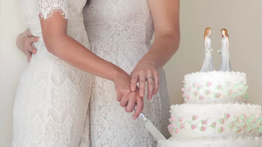 Two brides cutting wedding cake --- Image by © Ron Royals/Corbis