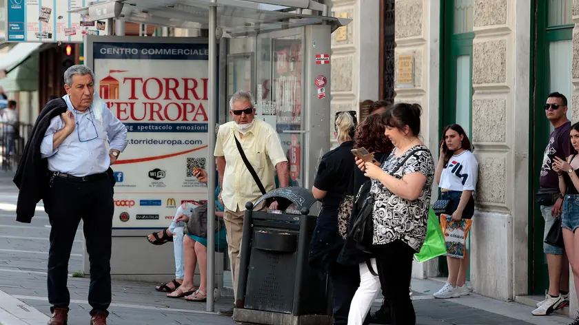 Persone in strada a Trieste, qualcuno con la mascherina al collo