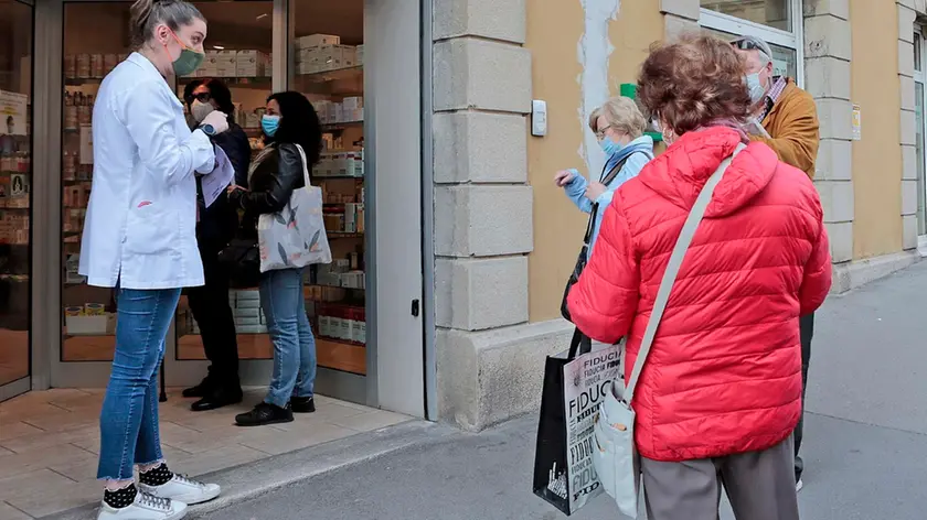 Triestini sopra i 70 anni decisi a prenotare la loro dose di vaccino anti Covid davanti alle vetrine della farmacia in piazza Foraggi a Trieste. Foto Massimo Silvano