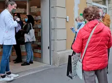 Triestini sopra i 70 anni decisi a prenotare la loro dose di vaccino anti Covid davanti alle vetrine della farmacia in piazza Foraggi a Trieste. Foto Massimo Silvano