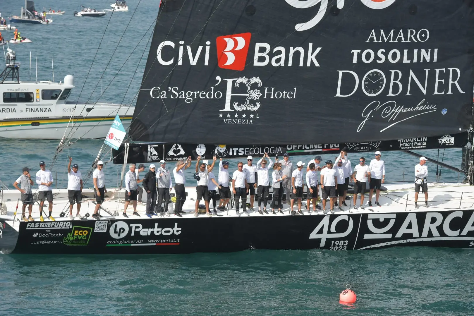 Arca Sgr del velista triestino Furio Benussi, leader del Fast and Furio Sailing Team, ha vinto la Barcolana numero 55 in un'ora 49 minuti e 55 secondi. La regata più grande del mondo questa mattina ha dato spettacolo nel golfo di Trieste con 1.773 vele in partenza in una giornata caratterizzata da pochissimo vento, tanto che la competizione si è chiusa alla prima boa. Al timone di Arca sulla linea di arrivo la giovanissima Marta, figlia di Furio Benussi, di soli 16 anni. Padre e figlia insieme si sono tuffati in segno di festeggiamento dal Molo Audace, dove si sono tenute le premiazioni. A consegnare il trofeo anche il Ministro per lo Sport e i Giovani Andrea Abodi, assieme al Presidente della Barcolana Mitja Gialuz il vincitore. Foto di Andrea Lasorte, Massimo Silvano e Francesco Bruni