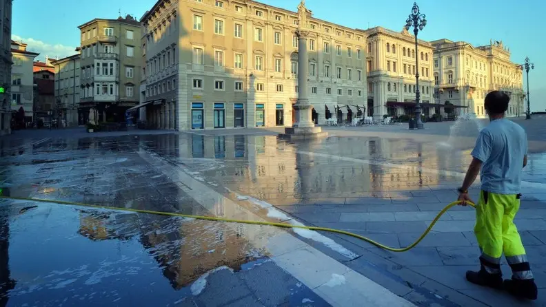 La pulizia di piazza Unità al mattino