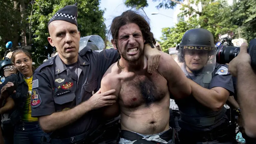 A protester is detained by police during a demonstration demanding better public services and protesting the money spent on the World Cup soccer tournament in Sao Paulo, Brazil, Thursday, June 12, 2014. Brazilian police clashed with anti-World Cup protesters trying to block part of the main highway leading to the stadium that hosts the opening match of the tournament. (AP Photo/Rodrigo Abd)