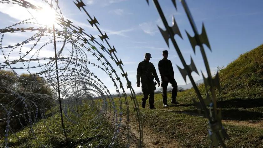 Due soldati sloveni passeggiano vicino al filo spinato