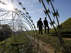 Due soldati sloveni passeggiano vicino al filo spinato